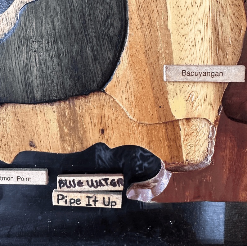 Wooden site map with a hand-labeled tag marking the newly named 'Bluewater' dive site.