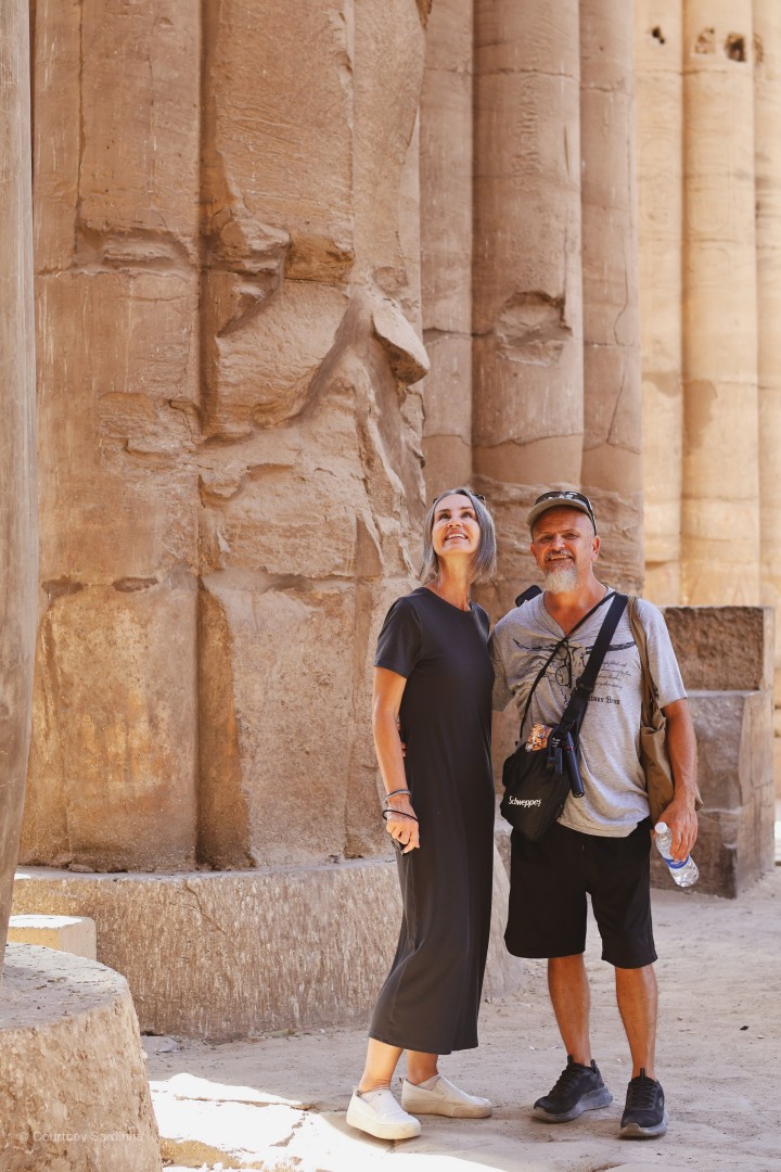 A couple standing beneath ancient columns at Luxor Temple, Egypt