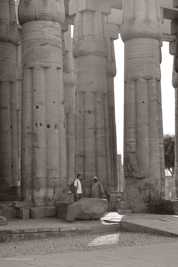 Visitors walking between towering columns at Luxor Temple, Egypt