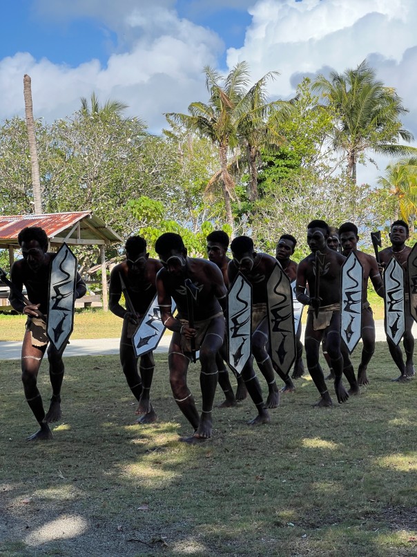 Village performers with traditional shields during a welcome dance
