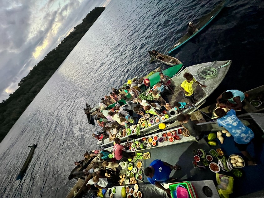 Villagers selling produce from canoes beside the Bilikiki at dusk