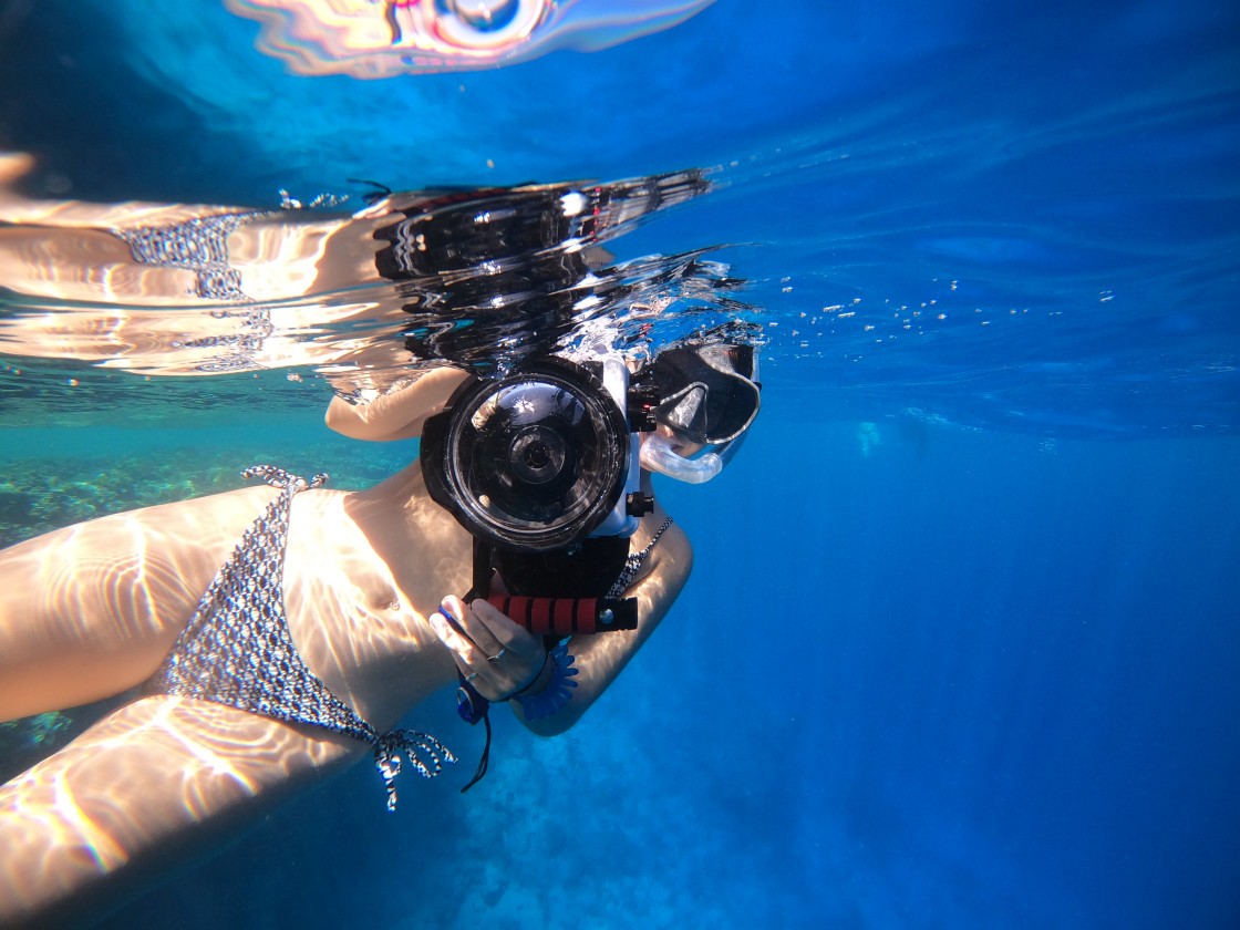 A snorkeller taking a photo underwater in the crystal clear Red Sea, Sharm el-Sheikh, Egypt